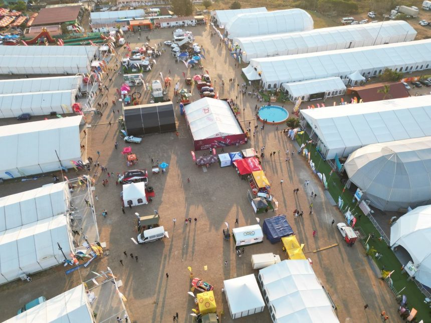 Vista aérea de uma feira ao ar livre movimentada, com tendas, estandes e visitantes.